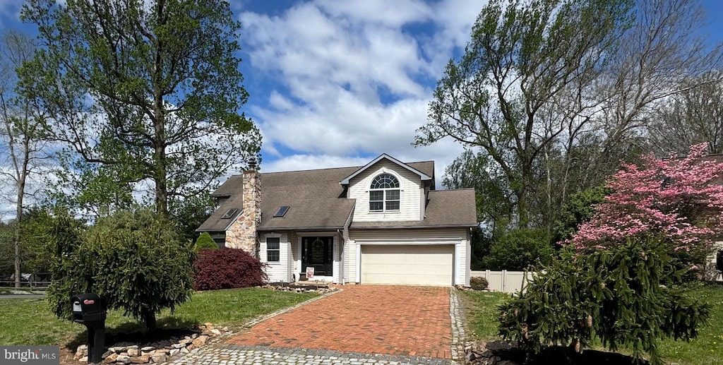view of front facade with a front lawn, decorative driveway, an attached garage, and fence