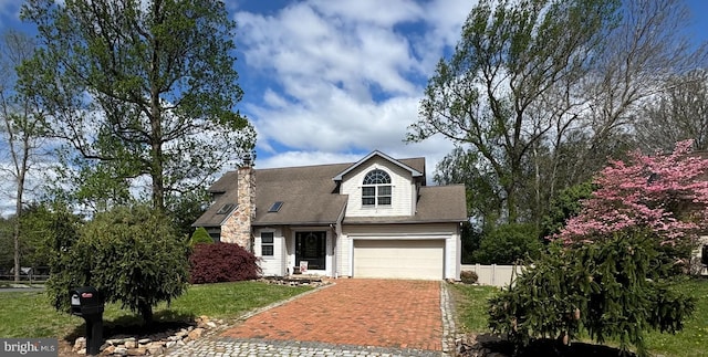 view of front facade with a front lawn, decorative driveway, an attached garage, and fence