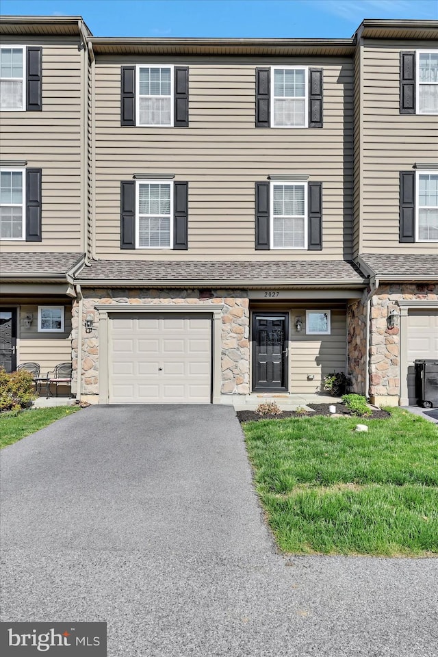 view of property featuring driveway, central AC, stone siding, and a garage