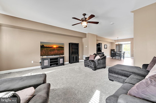 living room featuring visible vents, baseboards, carpet flooring, and ceiling fan with notable chandelier