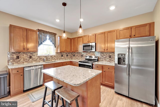 kitchen with appliances with stainless steel finishes, a center island, light wood-style floors, and a sink