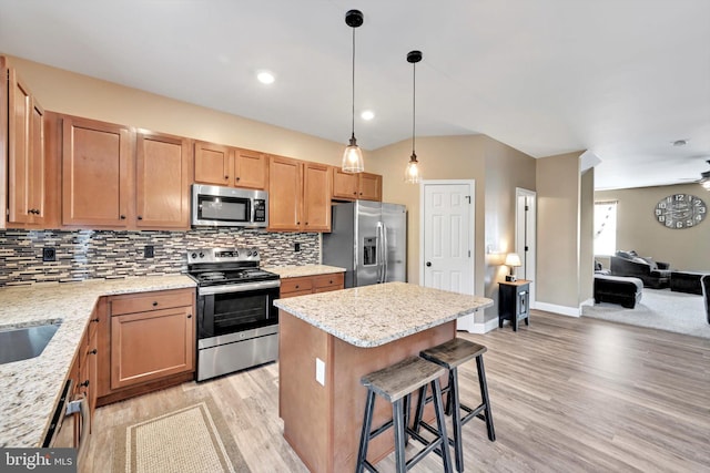 kitchen featuring a breakfast bar, stainless steel appliances, light wood-type flooring, and backsplash