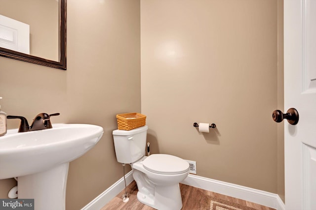 bathroom with toilet, a sink, wood finished floors, and baseboards