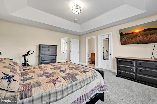 bedroom featuring connected bathroom, baseboards, carpet floors, and a tray ceiling