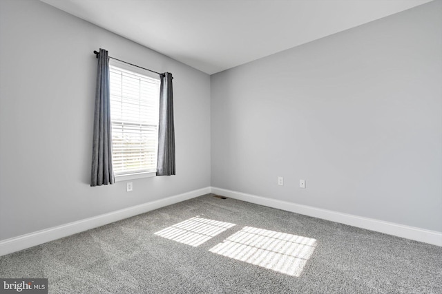 carpeted empty room featuring baseboards