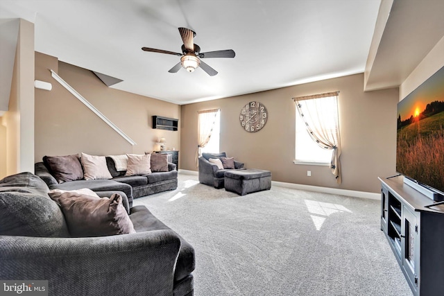 living area with a ceiling fan, carpet flooring, a wealth of natural light, and baseboards
