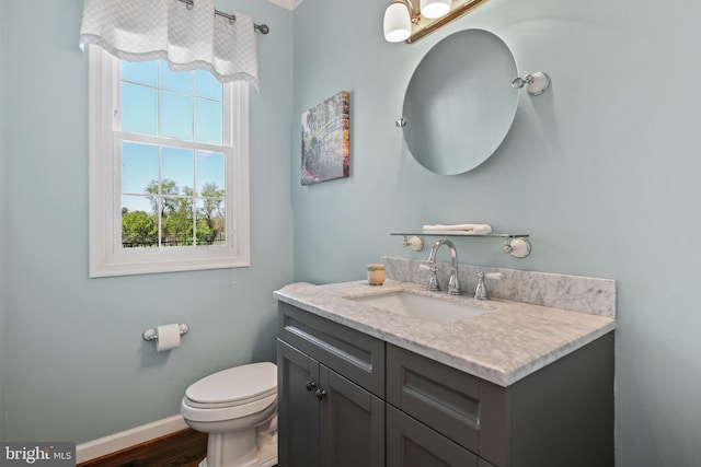 half bath featuring toilet, baseboards, wood finished floors, and vanity