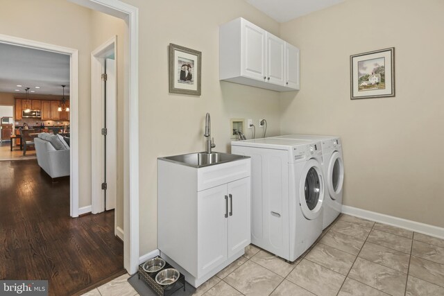 washroom with baseboards, a sink, cabinet space, and washing machine and clothes dryer
