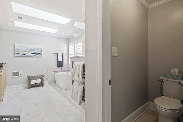 bathroom with crown molding, a freestanding bath, toilet, marble finish floor, and a skylight
