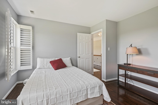 bedroom with baseboards, visible vents, and wood finished floors