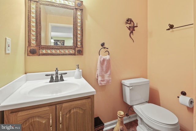 half bathroom with vanity, baseboards, and toilet