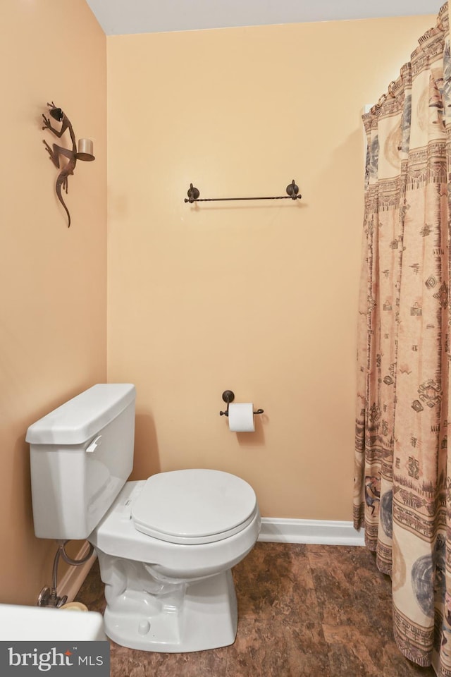 full bathroom featuring toilet, baseboards, and a shower with shower curtain