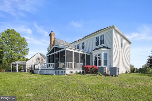 back of property with central air condition unit, a yard, and a sunroom