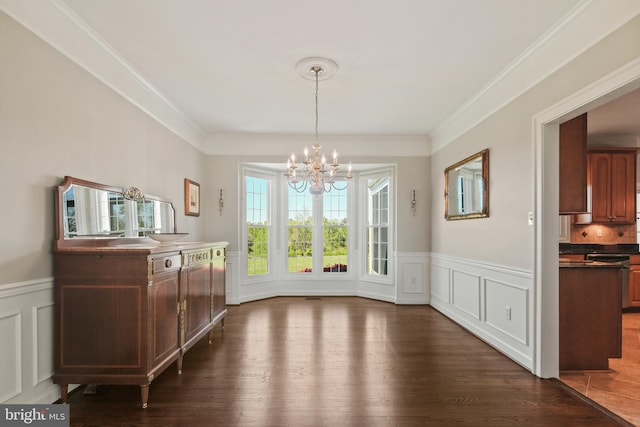 dining space featuring crown molding, an inviting chandelier, dark wood-style floors, and a decorative wall