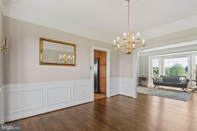 dining room featuring crown molding, a decorative wall, a wainscoted wall, dark wood finished floors, and a notable chandelier