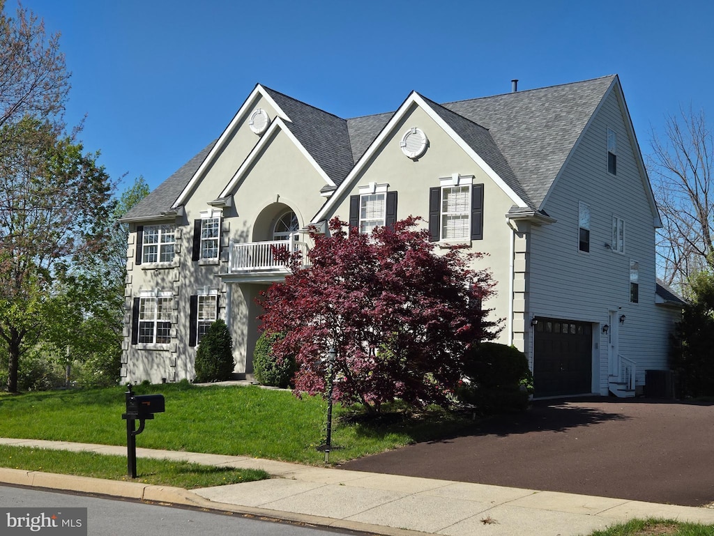 view of front of property with stucco siding, aphalt driveway, a garage, roof with shingles, and a front yard