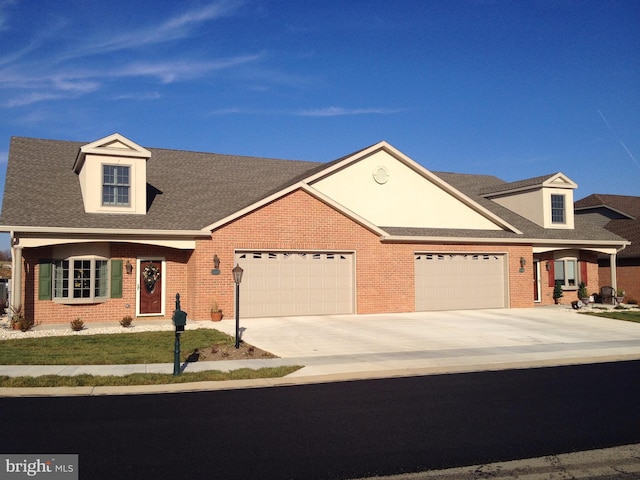 view of front of home with driveway, an attached garage, a shingled roof, and brick siding