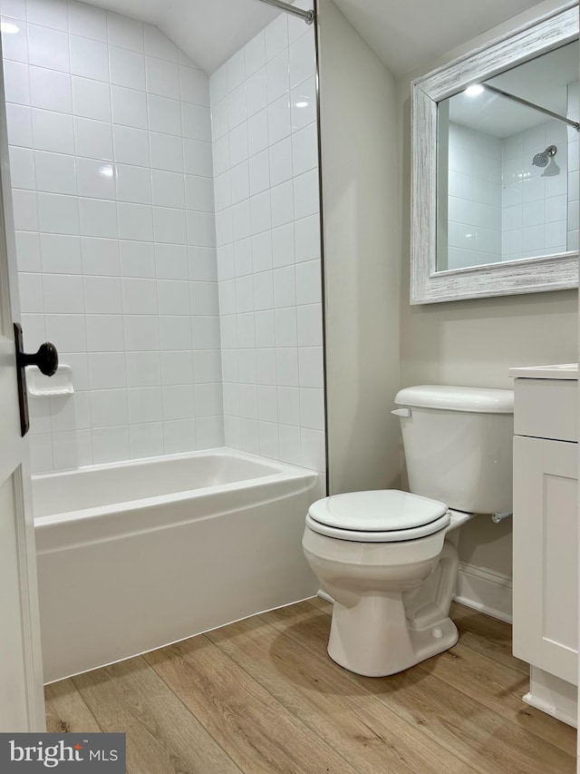 bathroom with wood finished floors, toilet, vanity, and bathing tub / shower combination