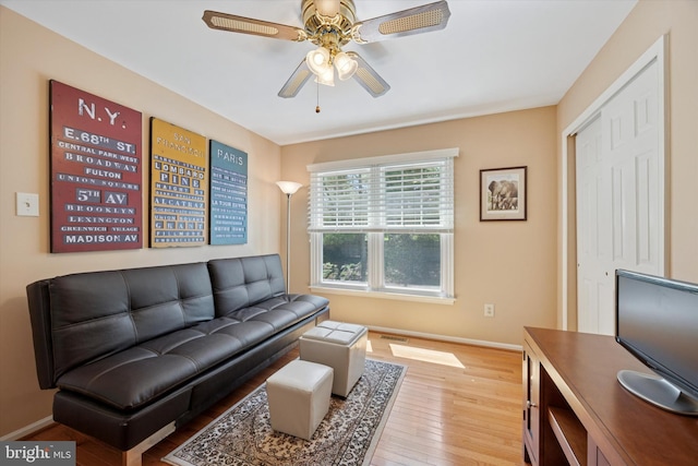 living room featuring a ceiling fan, visible vents, baseboards, and light wood-style floors
