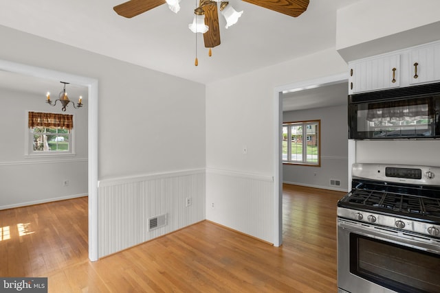 kitchen featuring black microwave, visible vents, light wood finished floors, and gas range