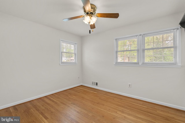 spare room with a ceiling fan, visible vents, light wood-style floors, and baseboards