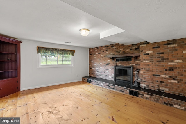 unfurnished living room featuring a fireplace, visible vents, hardwood / wood-style floors, and baseboards