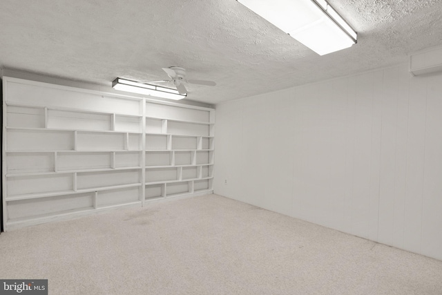 below grade area with a ceiling fan, a textured ceiling, and carpet flooring