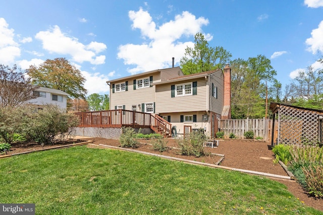 back of property featuring fence, a chimney, a yard, and a wooden deck