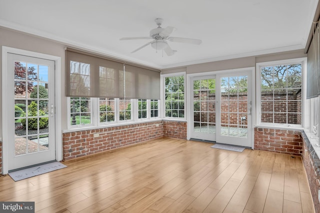 unfurnished sunroom with french doors, brick wall, a wealth of natural light, and wood finished floors