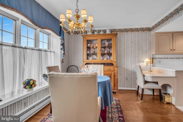 dining room with a notable chandelier, baseboards, wallpapered walls, wood finished floors, and a baseboard heating unit