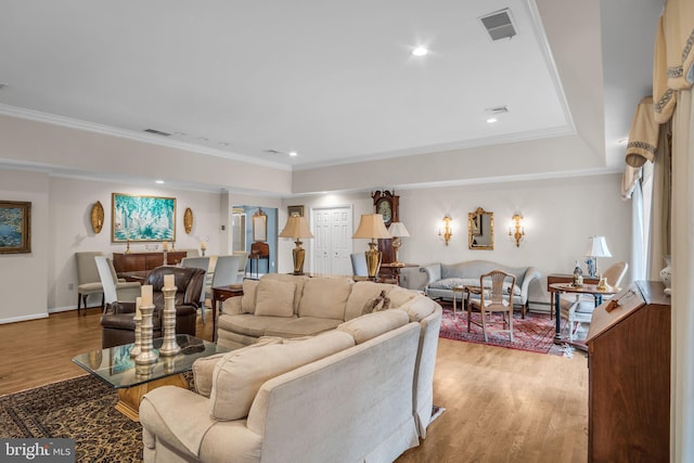 living area featuring baseboards, visible vents, ornamental molding, and wood finished floors