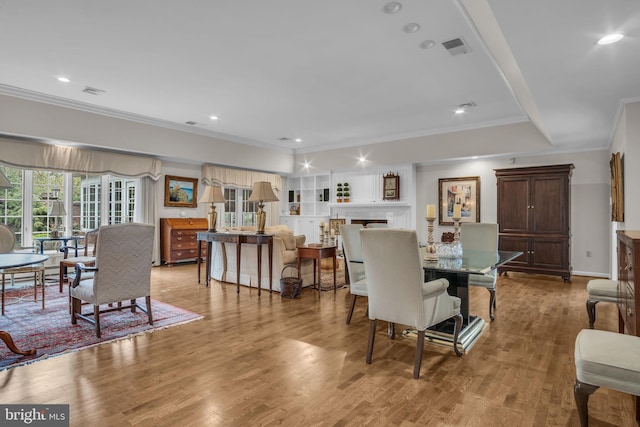 dining room featuring visible vents, ornamental molding, and light wood-style flooring