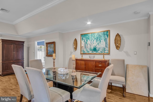dining room with a raised ceiling, light wood finished floors, recessed lighting, visible vents, and ornamental molding