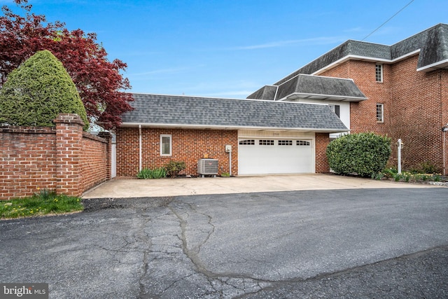 view of property exterior with brick siding, roof with shingles, and central AC