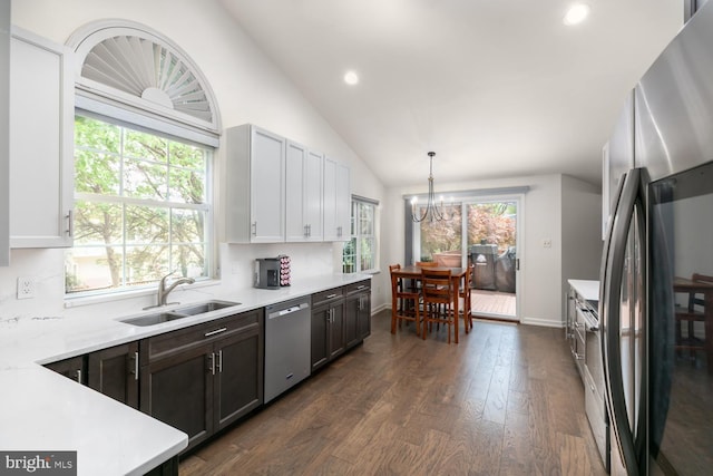 kitchen with appliances with stainless steel finishes, light countertops, a sink, a notable chandelier, and lofted ceiling