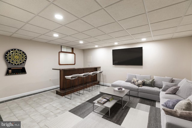 living area with a drop ceiling, recessed lighting, bar area, and baseboards