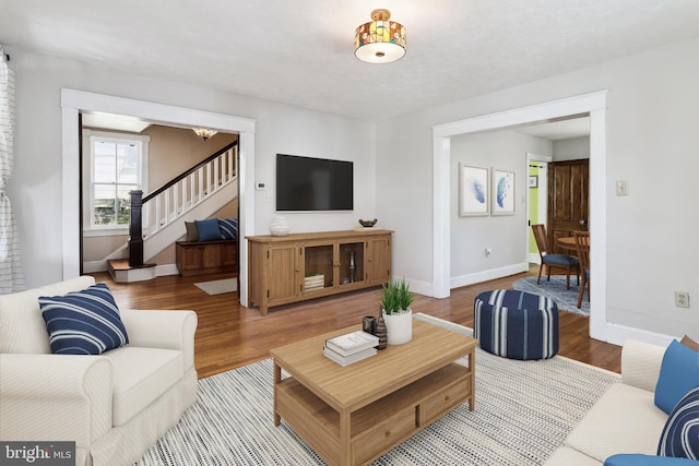 living area with baseboards, stairs, and wood finished floors