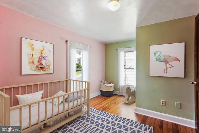 bedroom featuring baseboards, multiple windows, and hardwood / wood-style floors