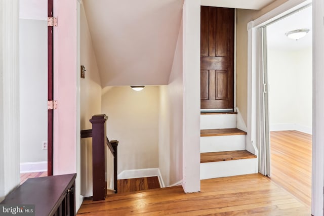 staircase featuring baseboards and wood finished floors