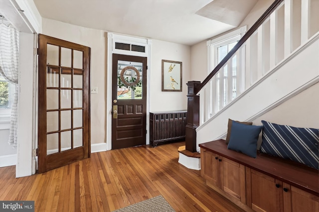 entryway featuring radiator, plenty of natural light, stairs, and light wood-style flooring