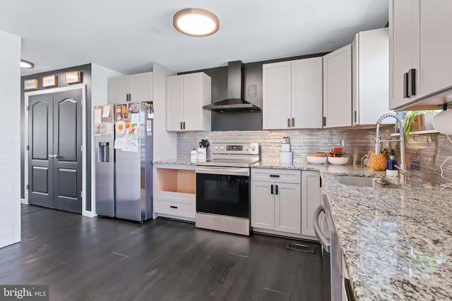 kitchen featuring wall chimney range hood, tasteful backsplash, a sink, stainless steel appliances, and dark wood-style floors