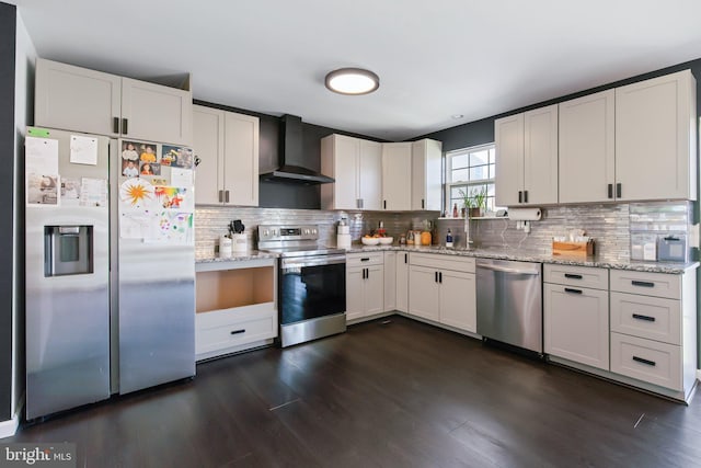 kitchen with light stone counters, appliances with stainless steel finishes, wall chimney range hood, and white cabinetry