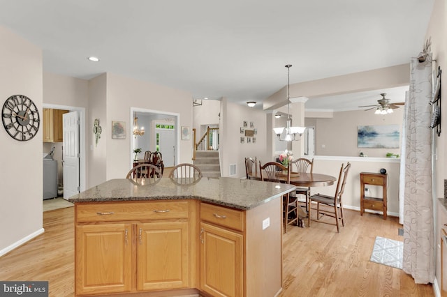 kitchen featuring stone countertops, light wood-style flooring, a center island, baseboards, and visible vents