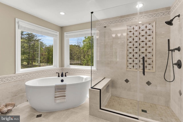 full bathroom featuring recessed lighting, tile walls, a soaking tub, and a stall shower