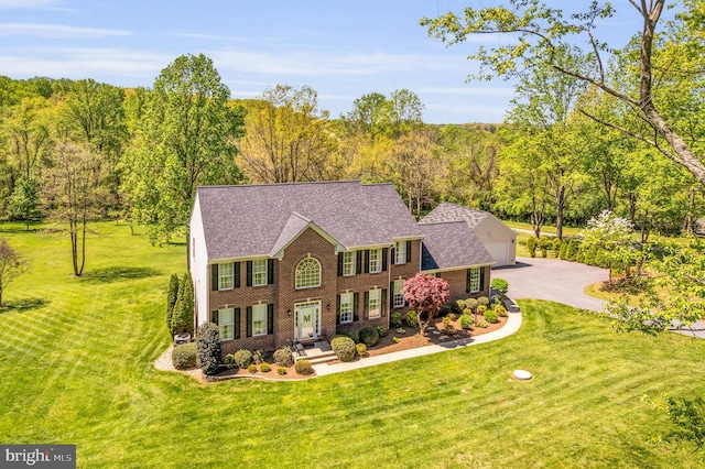 colonial inspired home with brick siding, a front lawn, and a detached garage