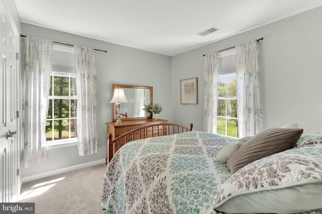 carpeted bedroom featuring baseboards, visible vents, and multiple windows