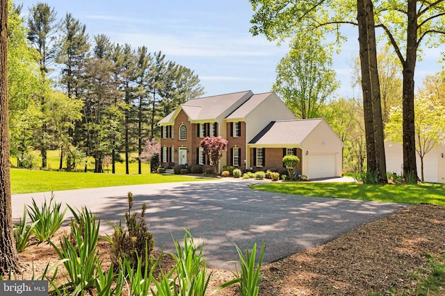 colonial house featuring brick siding, an attached garage, driveway, and a front lawn