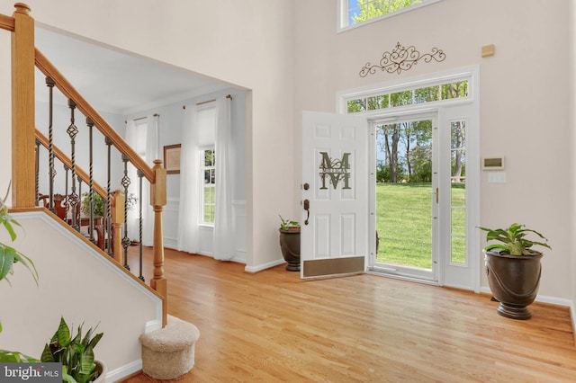 entrance foyer featuring stairway, baseboards, a high ceiling, and light wood finished floors