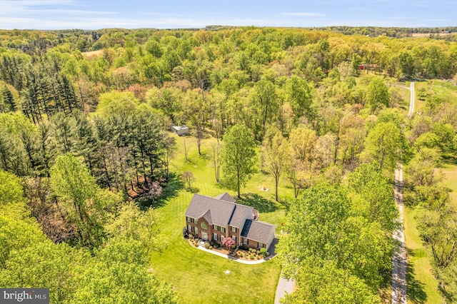 bird's eye view with a wooded view