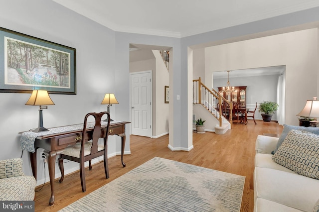 living area with baseboards, wood finished floors, a notable chandelier, and stairway